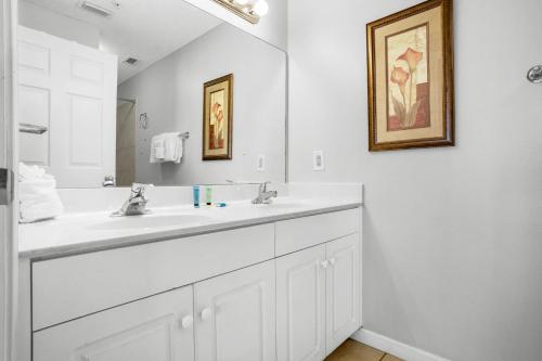 a white bathroom with a sink and a mirror at Majestic Sun 1012A in Destin