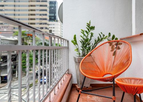 uma varanda com uma cadeira laranja na varanda em ZEST Pedroso em São Paulo