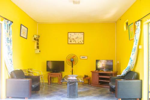 a yellow living room with chairs and a tv at Blooms Apartments in Pereybere