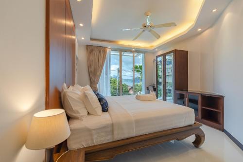 a bedroom with a bed with a ceiling fan and a window at White Villa Patong in Patong Beach