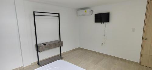 um quarto branco com uma cama e um espelho em Work space Hostal em Uribia