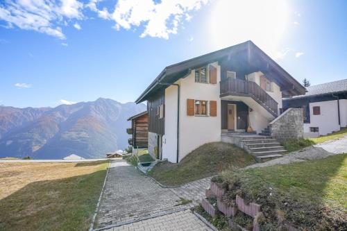 a house on a hill with mountains in the background at Serenella Apartment in Riederalp