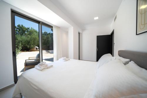 a bedroom with a white bed and a large window at Villa Vivian Heated Private Swimming Pool & Jacuzzi in Georgioupolis