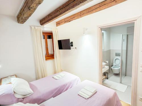 two beds in a room with a bathroom at Home Dren in Prepotto