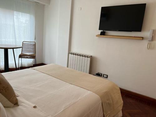 1 dormitorio con 1 cama y TV de pantalla plana en la pared en Alsina 728 con pileta UKIYO en Salta