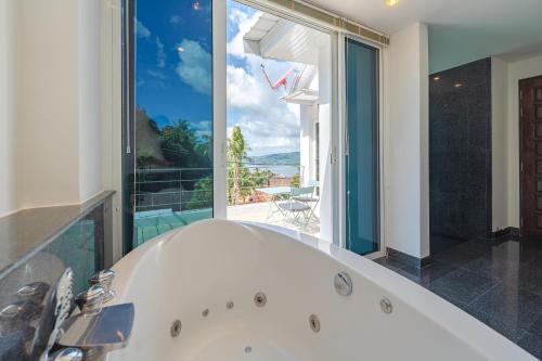 uma banheira na casa de banho com uma grande janela em White Villa Patong em Praia de Patong