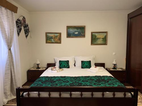 a bedroom with a bed with green sheets and pillows at CASA LUI MOȘU in Alba Iulia