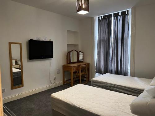 a hotel room with two beds and a flat screen tv at Scotland Beds in Dundee