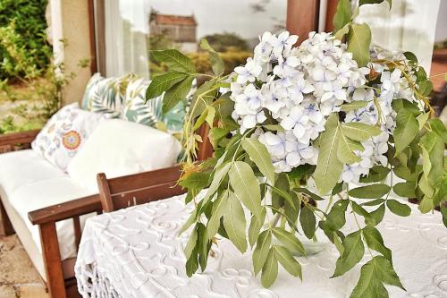 une table avec un tissu de table blanc et une plante dessus dans l'établissement Casa do Caseiro A Costa da Morte, à Jornes