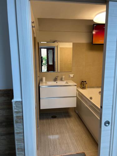 a bathroom with a white sink and a tub and a tubermott at Petite Suite in Naples