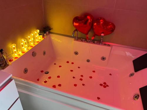 a bathroom with a tub with red hearts and candles at Petite Suite in Naples