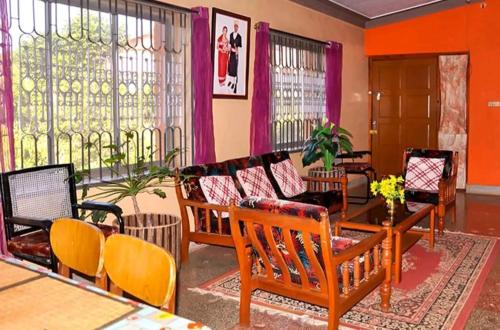 a living room with chairs and a couch and a table at Honey Palace Homestay in Madikeri