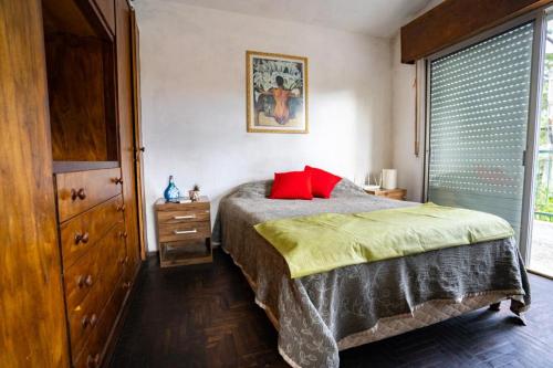 Schlafzimmer mit einem Bett mit roten Kissen und einem Fenster in der Unterkunft Hermoso apartamento en el centro de Atlántida in Atlántida