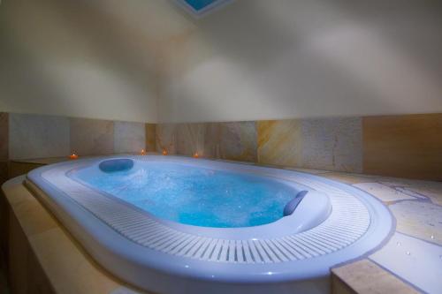 a jacuzzi tub in a bathroom with blue water at Garni Petra in Selva di Val Gardena