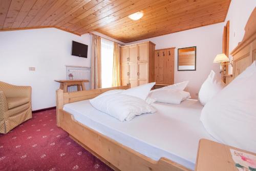 a bedroom with a large bed with white pillows at Garni Petra in Selva di Val Gardena