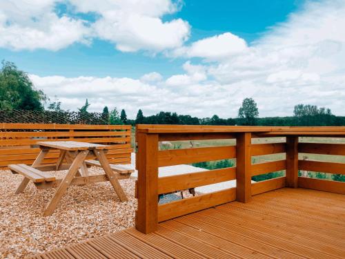 a wooden deck with a picnic table and a fence at Crabmill Glamping with hot tub in Bewdley