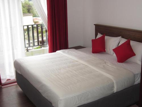 a bed with red pillows in a room with a window at Chanya Luxury Apartment, S 31, Lake View Residencies in Nuwara Eliya