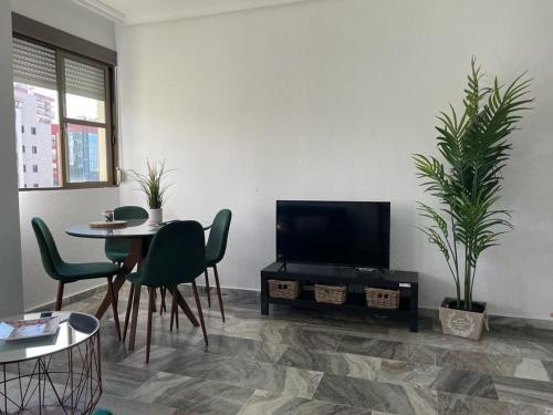 een woonkamer met een televisie en een tafel en stoelen bij Apartamento turístico La Joya in Huelva