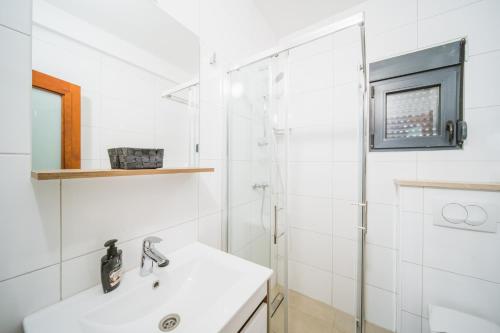 a white bathroom with a sink and a shower at Pansion Lipa in Blato