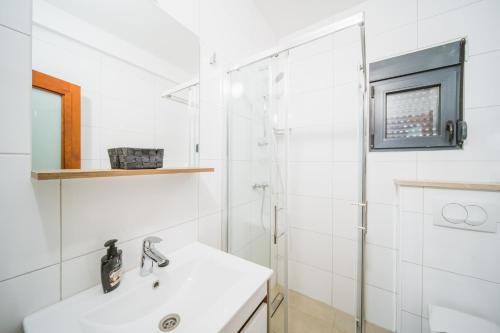 biała łazienka z umywalką i prysznicem w obiekcie Pansion Lipa w mieście Blato