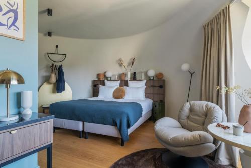 a bedroom with a bed and a chair at L'EssenCiel in Piré-sur-Seiche