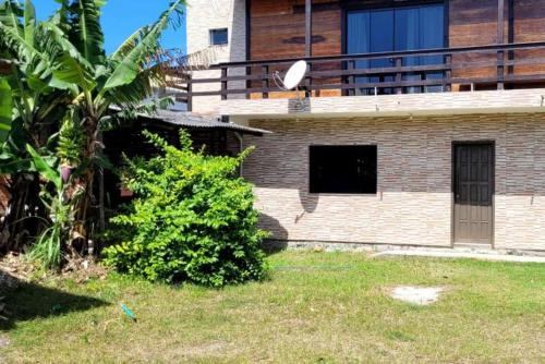 ein Backsteingebäude mit einem Fenster und einem Busch in der Unterkunft Borges House in Imbituba