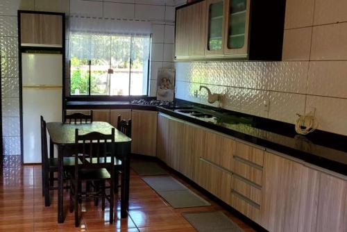 uma cozinha com uma mesa e cadeiras e uma cozinha com uma janela em Borges House em Imbituba