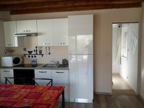 a kitchen with white cabinets and a kitchen table at Single storey 40m² bordering pine forest and spa in Noves