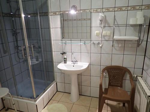 La salle de bains est pourvue d'un lavabo, d'une douche et d'une chaise. dans l'établissement Pokoje Gościnne w Centrum, à Szczyrk