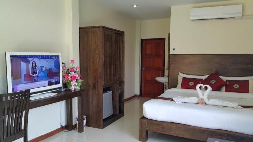 1 dormitorio con 1 cama y escritorio con TV en Ruen Narisra Resort, en Sukhothai