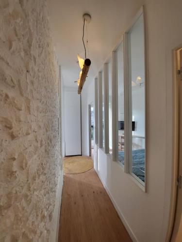 un couloir avec une rangée de fenêtres et un mur en pierre dans l'établissement Appartement La verrerie, terrasse et jardinet, à Cognac