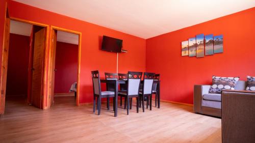 a dining room with orange walls and a table and chairs at cabañas laguna de zapallar maitencillo in Zapallar