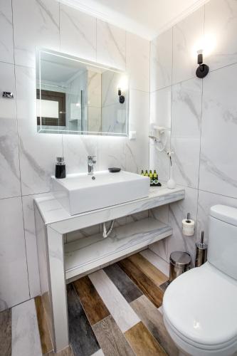 a white bathroom with a sink and a toilet at Ermioni Sea View Hotel in Limenaria