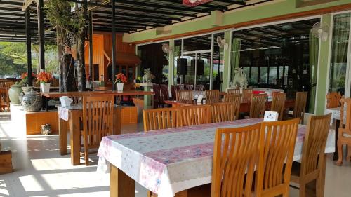 comedor con mesa, sillas y ventanas en Ruen Narisra Resort, en Sukhothai