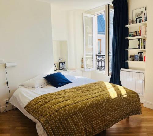 - une chambre avec un lit doté d'un oreiller bleu et d'une fenêtre dans l'établissement Marais - Appartement sur les toits, à Paris