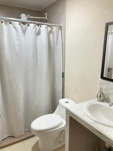 a white bathroom with a toilet and a sink at Hospedaje Ana Lu 2, Only 10 minutes from airport in Alajuela City