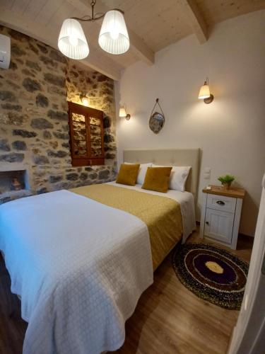 1 dormitorio con cama y pared de piedra en Rodanthe's Guest House, en Stemnitsa