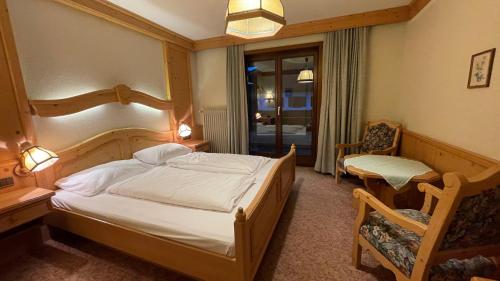 1 dormitorio con 1 cama, 1 silla y 1 ventana en Hotel Alpenrose, en Zöblen