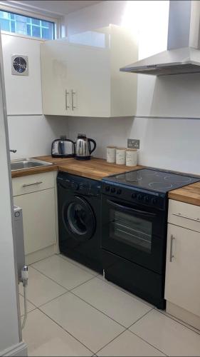 een keuken met een zwarte kachel en een wasmachine bij City of London in Londen