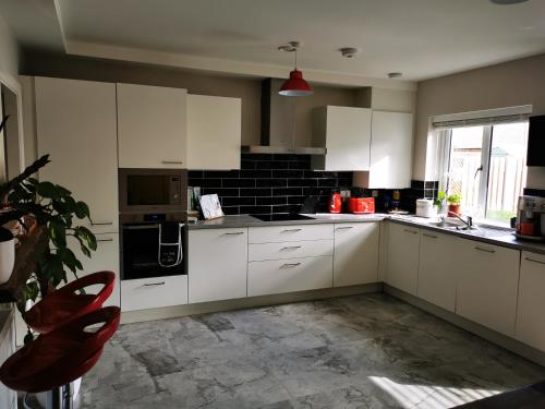 una cocina con armarios blancos y una silla roja. en Cozy room in Lucan, en Lucan