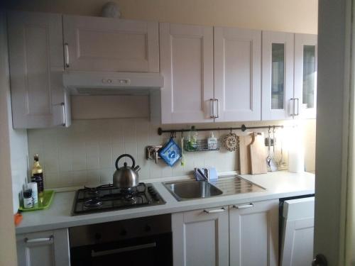 a kitchen with white cabinets and a sink and a stove at Il giardino di Olivia in Guarene