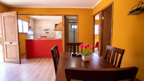 a dining room with a table and a kitchen at cabañas laguna de zapallar maitencillo in Zapallar