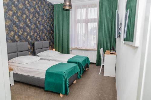 a bedroom with a bed with green curtains and a window at The Old Townhouse in Krosno