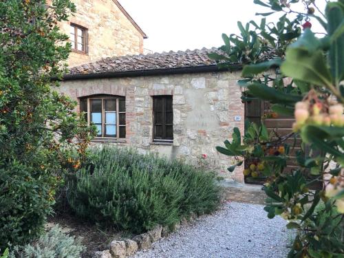 a stone house with a garden in front of it at Country House Girasole Crete Senesi Vakantie Huis in Asciano