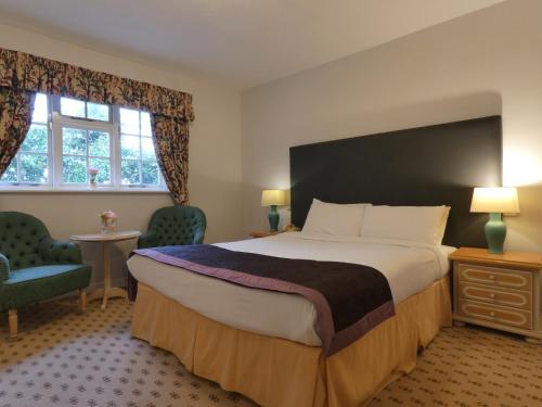 a hotel room with a large bed and two chairs at Marston Farm Hotel in Sutton Coldfield
