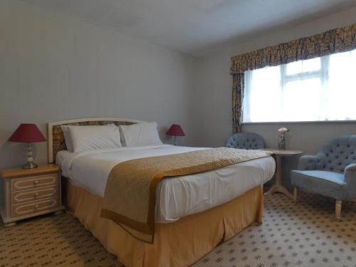 a bedroom with a bed and a chair and a window at Marston Farm Hotel in Sutton Coldfield