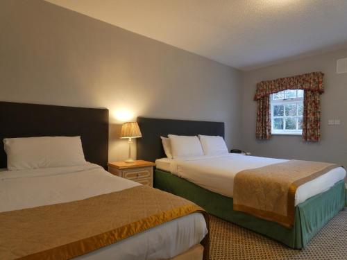 a hotel room with two beds and a window at Marston Farm Hotel in Sutton Coldfield