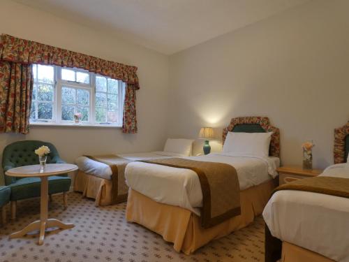 a room with two beds and a table and a window at Marston Farm Hotel in Sutton Coldfield