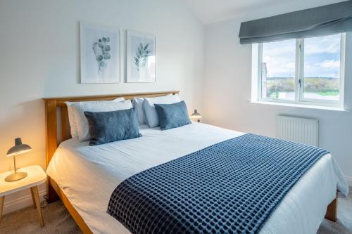 a bedroom with a blue and white bed with two windows at The Lookout in Wells next the Sea