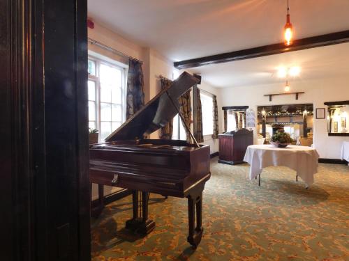 a piano sitting in a room with a table at Marston Farm Hotel in Sutton Coldfield